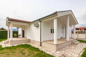 uma casa branca com colunas e um pátio em Deluxe Holiday Home-Podgorica em Podgorica