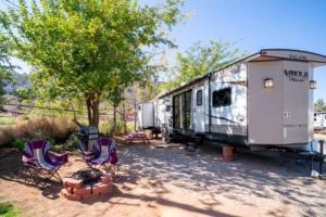 an rv parked next to chairs and a tree at Moab RV Resort RV Fully Setup OK41 in Moab