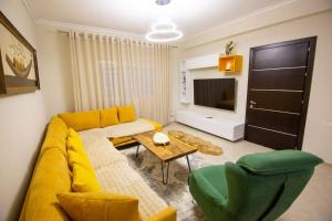 a living room with a yellow couch and a tv at Luxury House in Korçë