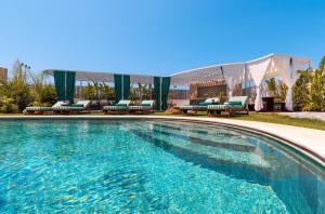 a large swimming pool with chairs and a building at Voger Alaçatı Prive in Cesme