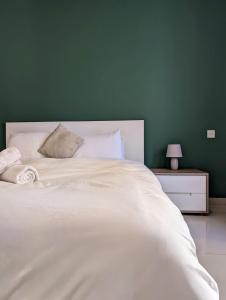 sypialnia z dużym białym łóżkiem i zieloną ścianą w obiekcie Central & 1 min walk to the sea! "The Gallery" Apartment, Sliema w mieście Sliema