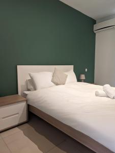 um quarto com uma grande cama branca e uma parede verde em Central & 1 min walk to the sea! "The Gallery" Apartment, Sliema em Sliema