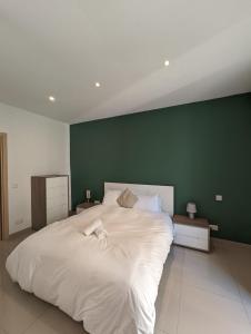 1 dormitorio con 1 cama blanca grande y pared verde en Central & 1 min walk to the sea! "The Gallery" Apartment, Sliema, en Sliema
