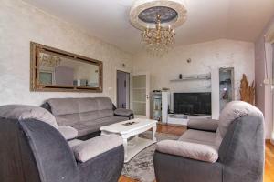 uma sala de estar com sofás e um lustre em Deluxe Holiday Home-Podgorica em Podgorica