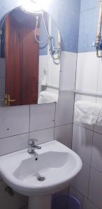y baño con lavabo blanco y espejo. en Mont Carmel Hotel en Gisenyi