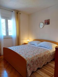 een slaapkamer met een groot bed met een klok aan de muur bij Apartment Ivan in Trogir