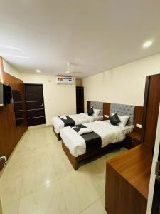 a hotel room with two beds and a television at Royal Plaza City in Kozhikode