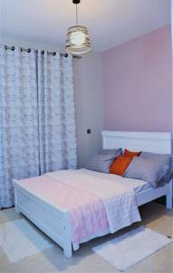 a bedroom with a white bed and a window at Alo's Apartment_KISASI in Kampala