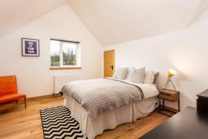 a white bedroom with a bed and a chair at Windhover Barn in Annbank