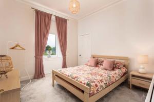 um quarto com uma cama com almofadas cor-de-rosa e uma janela em Castlehill Road em Ayr