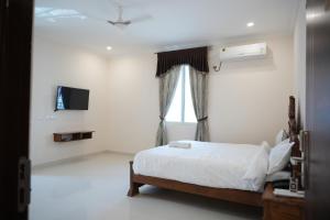 a white bedroom with a bed and a window at SABA SERVICE APARTMERNT in Hyderabad