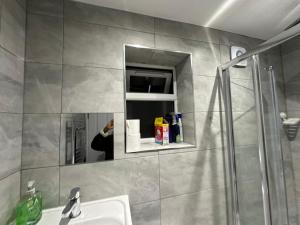 una persona che scatta una foto in uno specchio del bagno di 2nd Studio Flat With Great Views in Keedonwood Road With Private Kitchenette and shared bathroom a Bromley