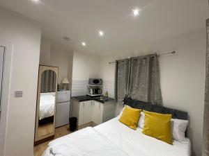 um quarto com uma cama branca e almofadas amarelas em 2nd Studio Flat With Great Views in Keedonwood Road With Private Kitchenette and shared bathroom em Bromley