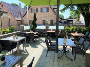 eine Außenterrasse mit Tischen und Stühlen sowie einem Pool in der Unterkunft Landgasthof Hotel Grüner Baum in Nürnberg