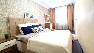 een slaapkamer met een groot bed en een raam bij 2 комнатная квартира в центре города in Karagandy