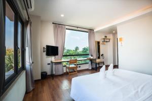 a bedroom with a bed and a desk and a window at Siri Hotel in Vientiane