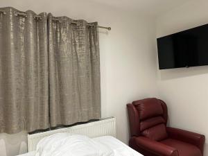 ein Schlafzimmer mit einem Bett, einem Stuhl und einem TV in der Unterkunft 2nd Studio Flat With Great Views in Keedonwood Road With Private Kitchenette and shared bathroom in Bromley