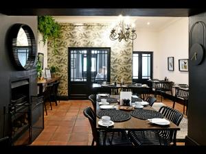 una sala da pranzo con tavoli, sedie e lampadario a braccio di Ashbourne Boutique Guest House a Franschhoek