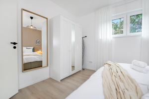 a white bedroom with a mirror and a bed at Stil und Komfort - Terrasse - Internet in Bielefeld