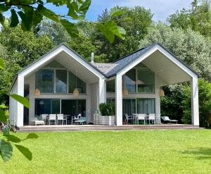 Casa con ventanas grandes y césped verde en Seechalet Faaker See, en Drobollach am Faakersee