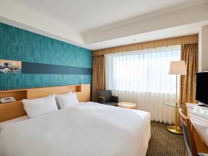東京にある東武ホテルレバント東京の白いベッドと窓が備わるホテルルームです。