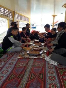 a group of people sitting around a table with food at Salah El Din Restaurant on the Nile Corniche in Aswan