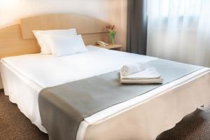 1 dormitorio con 1 cama blanca grande y toallas. en ARIBĖ Hotel Klaipėda, Free parking, en Klaipėda