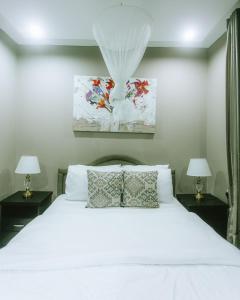 a bedroom with a white bed with two lamps at The Hatua Peaceful Homeaway Haven in Arusha