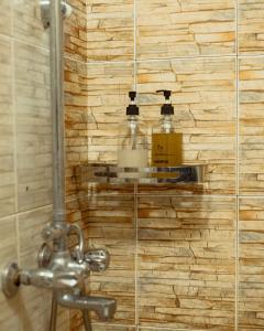 uma casa de banho com chuveiro e 2 garrafas na parede em The Hatua Peaceful Homeaway Haven em Arusha
