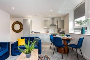 Bright 1 Bedroom Apartment in Central Rotherham في روثيرهام: مطبخ وغرفة معيشة مع كراسي زرقاء وطاولة