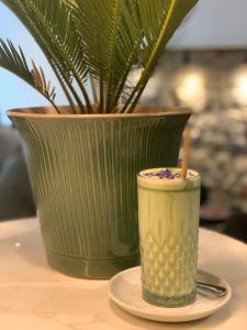 una taza verde en un plato junto a un jarrón en Appart Hôtel Victoria en Vincennes