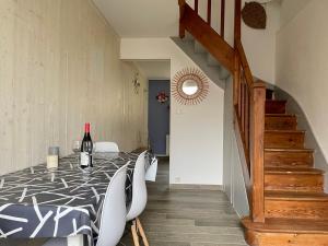 a dining room with a table with chairs and a bottle of wine at Beach House & Patio by Melrose in Arromanches-les-Bains +24 photos