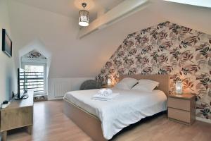 a bedroom with a large white bed with a floral headboard at Villa Mi-Syl- Jolie maison en pierre à Quévert in Quévert