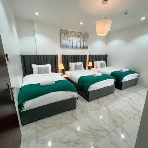 a bedroom with two beds with green and white sheets at Almasarat Tower Sea View in Jeddah