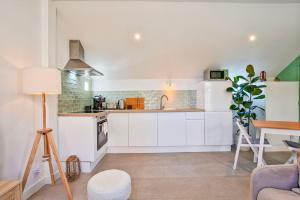 a kitchen with white cabinets and a table at L'Air Marin - Calm & cosy house by the sea in Ouistreham