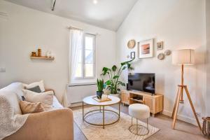 a living room with a couch and a tv and a table at L'Air Marin - Calm & cosy house by the sea in Ouistreham