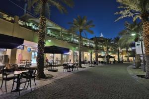 a courtyard with tables and chairs and palm trees at night at Spice Hotel in Kuwait