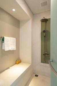 La salle de bains est pourvue d'une douche et de serviettes murales. dans l'établissement The Shells Resort & Spa Phu Quoc, à Duong Dong