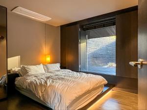 1 dormitorio con cama y ventana en Banwol Poolvilla en Busan
