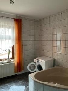 a bathroom with a tub and a washing machine at Apartment an der Honigbar in Leipzig