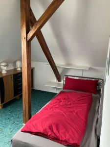 Una cama roja en una habitación con vigas de madera. en Apartment an der Honigbar en Leipzig