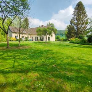 a house in a field of green grass with trees at La Lumineuse du Moulin in Saint-Germain-sur-Bresle