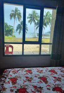 een slaapkamer met een raam met uitzicht op het strand bij Taman Baloho Indah - Hotel & Resort in Telukdalem