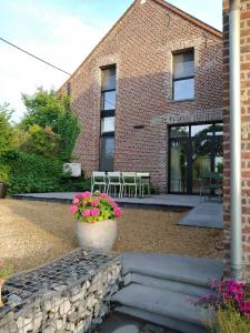 a brick building with a patio with tables and flowers at B&B De Woestijn in Roosdaal