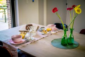 a table with flowers and cups and vases on it at B&B De Woestijn in Roosdaal