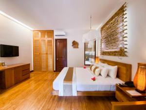 een slaapkamer met een bed, een bureau en een televisie bij Bamboo Village Beach Resort & Spa in Mũi Né