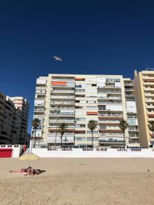 ein Gebäude am Strand mit Leuten am Strand in der Unterkunft ARENA y Mar Sunny Home by Cadiz4Rentals in Cádiz