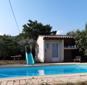 uma pequena casa com uma piscina e um escorrega azul em Villa conviviale au soleil avec piscine em Seillans