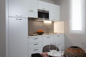 a kitchen with white cabinets and a table with wine glasses at Noba Hotel e Residenze in Rome