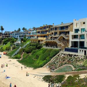a beach with a group of people and buildings at Datu - Discover world with us in Newport Beach